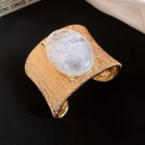 Primo piano di un bracciale rigido dorato retrò con finitura strutturata e pietra ovale