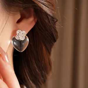 Detail of crystal zircon clover stud with transparent resin heart dangle