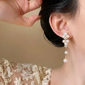 Close-up of elegant French style pearl drop earrings with zircon details on model's ear.