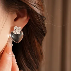 Close-up detail of silver needle zircon resin heart-shaped earring worn on ear