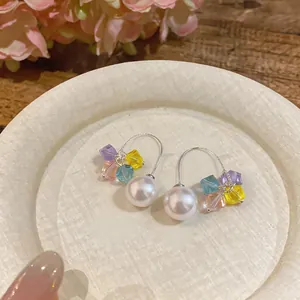 Detailed macro view of elegant curved earrings with white pearl and colorful crystals