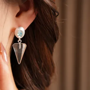Detailed close-up showing an ice blue zircon and resin triangular cone drop earring on a female ear.