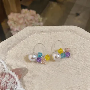 Exquisite close-up of fresh pearl hoop earrings with colorful crystal beads on beige linen