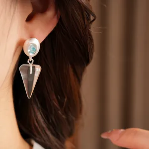 Detailed macro shot of ice blue resin drop earrings with triangular cone dangle worn on ear