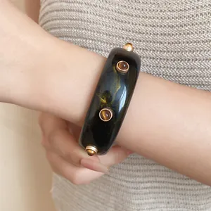 Detailansicht eines schwarzen Vintage-Harzarmreifs mit Goldmarmorierung und Nieten