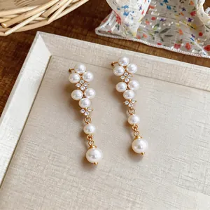 Close-up of elegant French pearl and zircon drop earrings on a textured display card.