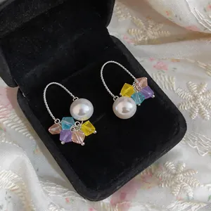 Close-up detail of elegant pearl earrings with vibrant colorful crystal accents on jewelry box