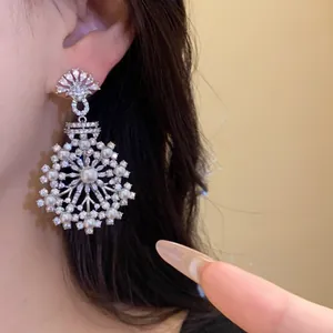 Vue détaillée d'une élégante boucle d'oreille fleur en argent avec zircon et perle sur modèle