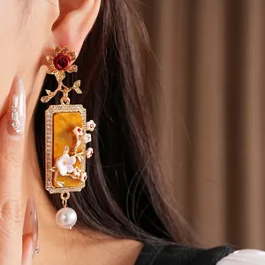 Boucles d'oreilles vintage fleur or avec perles et plaque résine ambre sur modèle