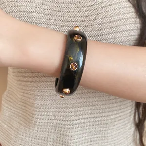 Detailansicht eines Retro-Harzarmbands mit dekorativen goldenen Nieten am Handgelenk