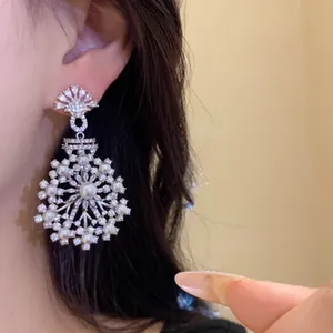 Gros plan de boucles d'oreilles fleurs élégantes avec perles blanches et zircons brillants