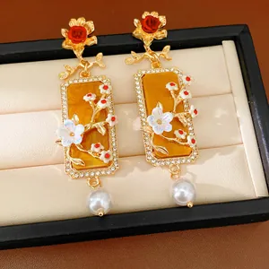 Détail rapproché de boucles d'oreilles carrées vintage avec fleurs, perles blanches et strass