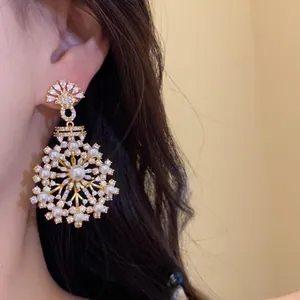 Boucles d'oreilles pendantes dorées élégantes avec perles et zircons, design floral.