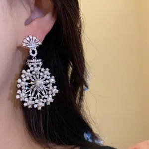 Vue détaillée des boucles d'oreilles en argent avec zircons et perles en forme de fleur.