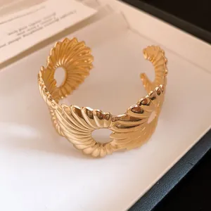 Nahaufnahme eines minimalistischen goldenen Falten-Armreifs mit runden Ausschnitten