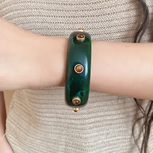 Detailaufnahme eines vintage grünen Marmor-Resin-Armreifs mit bernsteinfarbenen Nieten