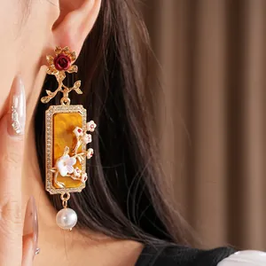 Gros plan de boucles d'oreilles vintage avec panneau ambre carré et perle blanche
