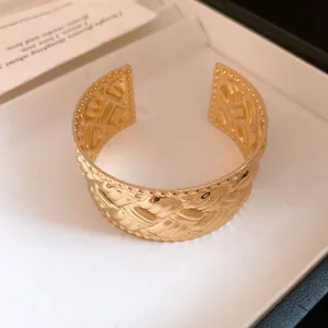 Detailansicht eines goldfarbenen geflochtenen breiten Armreifs mit Perlenrand-Design.