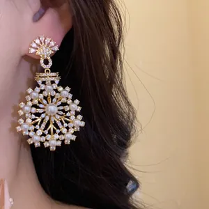 Gros plan de boucles d'oreilles pendantes fleurs avec perles et zircons sur modèle
