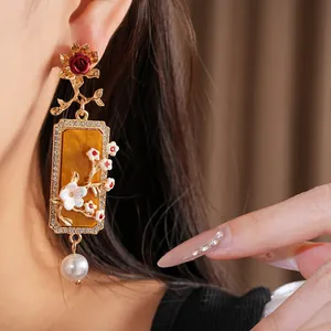 Détail de la boucle d'oreille vintage fleurie en or avec perle et résine ambrée