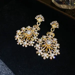 Gros plan d'élégantes boucles d'oreilles fleur avec zircons et perles sur velours noir.