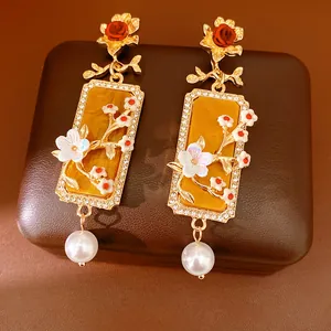 Vue détaillée de boucles d'oreilles vintage dorées avec roses rouges, cristaux et perles
