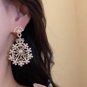 Élégantes boucles d'oreilles pendantes en zircon et perles portées par un mannequin
