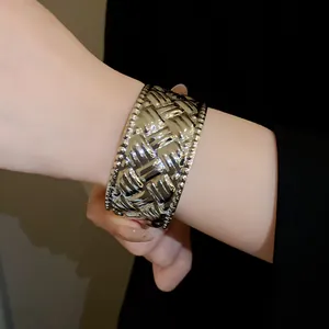 Detailansicht eines silbernen breiten Manschettenarmbands mit Faltenstruktur am Handgelenk