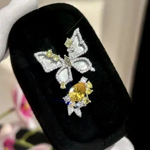 Macro view of exquisite butterfly and yellow zircon flower rings on black velvet