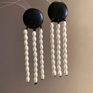 Elegant vintage round black wood earrings featuring long, dangling pearl tassel drops.