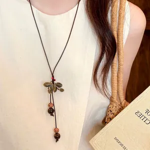 Close-up detail of a vintage style bronze leaf pendant necklace with natural brown beads