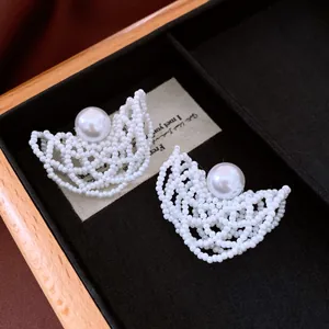 Primo piano di eleganti orecchini a perla intrecciata con grande perla centrale bianca
