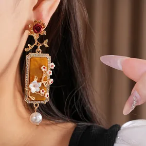 Détail de boucles d'oreilles vintage avec motifs floraux et perles pendantes