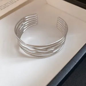 Nahaufnahme des eleganten silbernen mehrlagigen Streifendesigns der offenen Armspange.