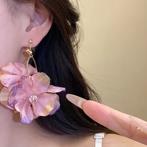 Primo piano di orecchini a fiore in tessuto rosa indossati da una modella