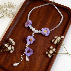 Dettaglio di una collana di fiori in tessuto in stile coreano con eleganti perle su legno