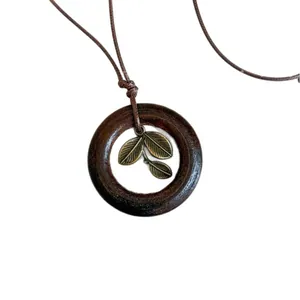 Vintage Bohemian wooden circle necklace with bronze leaf pendants and adjustable brown cord.