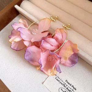 Dettaglio ravvicinato di orecchini a cerchio con fiori in tessuto viola romantico