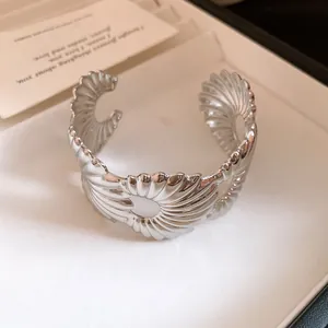 Detailaufnahme eines silberfarbenen, plissierten, offenen Armreifs für Damen.