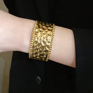 Detailansicht eines goldenen Hammerschlag-Armreifs mit eleganten Perlenrändern am Arm.