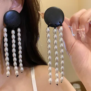 Close-up detail of vintage black wooden earrings featuring elegant white pearl tassel drops.