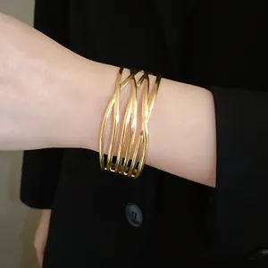 Detailansicht eines minimalistischen, goldfarbenen, offenen Armreifs am Handgelenk einer Frau