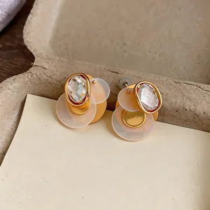 Close-up detail showing the texture of geometric 18k gold-plated earrings with zircon