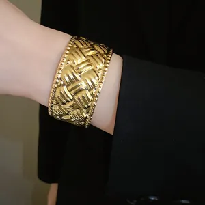 Detailansicht eines goldenen Armreifs mit plissierter Webstruktur und Perlenrand