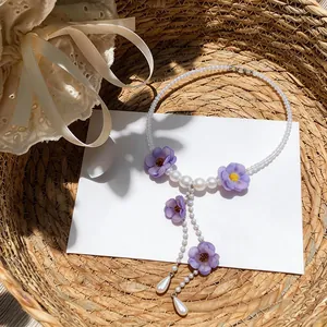 Vista dettagliata dell'elegante collana di fiori in tessuto viola con perline e nappe.