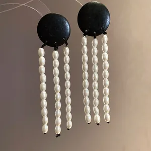Detailed macro view of vintage black wooden stud earrings featuring elegant white pearl tassels