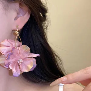Dettaglio di eleganti orecchini a sospensione in tessuto viola indossati da una modella