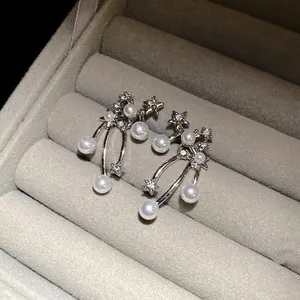 Dettaglio di orecchini d'argento con stelle e perle in un portagioie di velluto