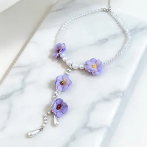 Elegante vista dettagliata dei fiori in tessuto viola e delle perle su una collana lariat