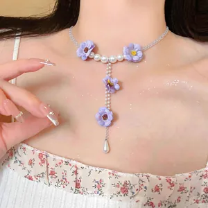 Primo piano di una collana di fiori in tessuto lavanda con nappe di perle su collo elegante